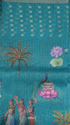 Embroidered fabric with palm tree, lotus flowers, and people design on a blue background