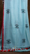 Light blue fabric with black eye designs and red accents on a brown background