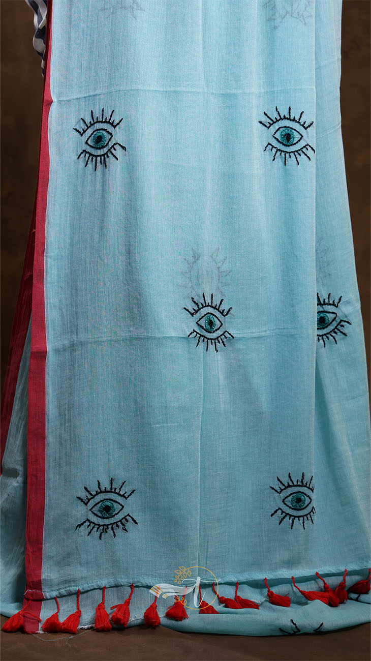 Light blue fabric with black eye designs and red accents on a brown background