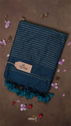 Blue striped towel with pom-pom trim on a brown background with decorative elements.