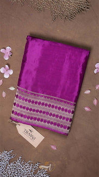 Purple fabric with a patterned border on a brown background with decorative elements.