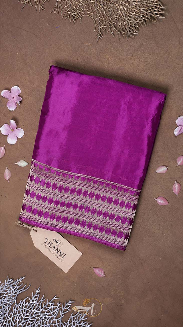 Purple fabric with a patterned border on a brown background with decorative elements.