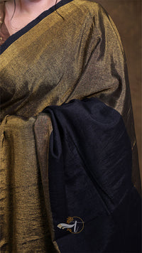 Close-up of a person wearing a gold and black garment with a visible brand logo.