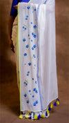 White saree with blue floral patterns and yellow border, worn by a person.
