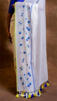 White saree with blue floral patterns and yellow border, worn by a person.