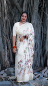 Woman in a floral saree standing in front of a large tree with thick trunk