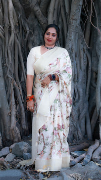 Woman in a floral saree standing in front of a large tree with thick trunk