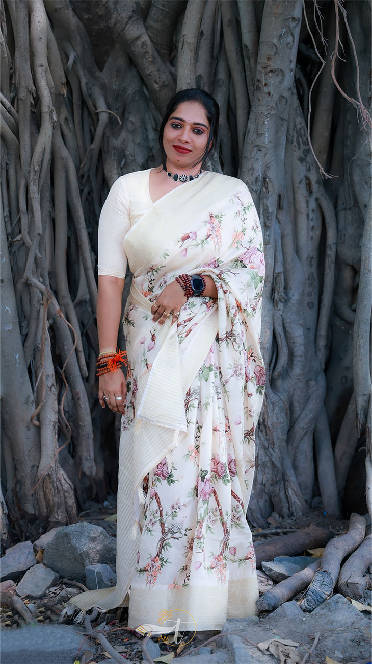 Woman in a floral saree standing in front of a large tree with thick trunk
