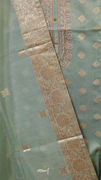 Close-up of a green fabric with intricate gold patterns
