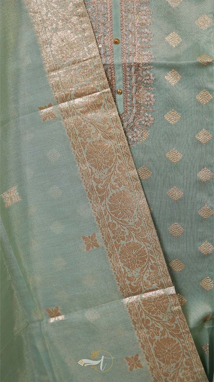 Close-up of a green fabric with intricate gold patterns