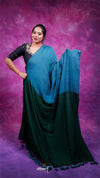 Woman wearing a blue and green saree against a purple background