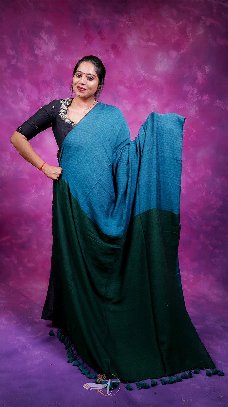 Woman wearing a blue and green saree against a purple background