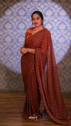 Woman in a brown saree with a patterned background