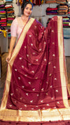 Woman holding a maroon saree with gold border in a store setting