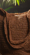 Close-up of a brown textured bag with a blurred green plant background