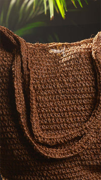 Close-up of a brown textured bag with a blurred green plant background