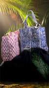 Two patterned bags on a dark surface with a blurred natural background