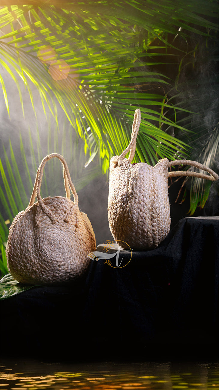 Two woven bags on a dark surface with green foliage in the background
