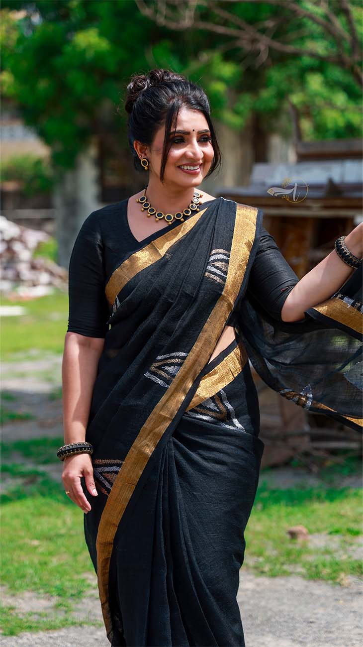 Woman in a black saree with gold border outdoors