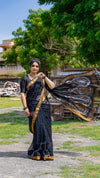 Woman in a black saree with gold border outdoors