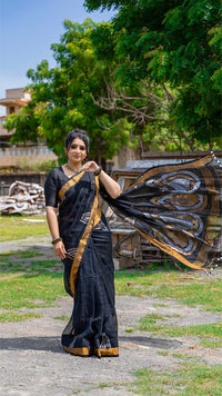 Woman in a black saree with gold border outdoors