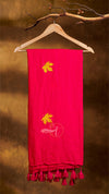 Red scarf with floral embroidery and tassels on a wooden hanger against a brown background