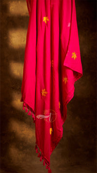 Red fabric with yellow patterns and tassels on a brown background