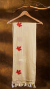 Beige scarf with red leaf designs hanging on a wooden hanger against a brown background