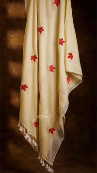 White fabric with red floral patterns and tassels on a dark background