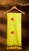 Yellow scarf with red leaf designs and tassels on a wooden hanger against a brown background