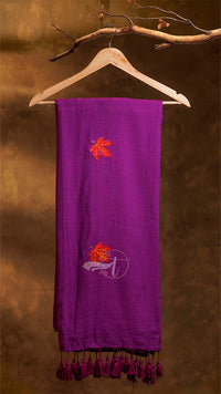 Purple scarf with embroidered designs on a wooden hanger against a brown background