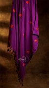Purple fabric with orange floral patterns and tassels on a brown background