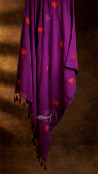 Purple fabric with orange floral patterns and tassels on a brown background