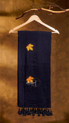 Navy blue scarf with embroidered leaf design on a wooden hanger against a brown background