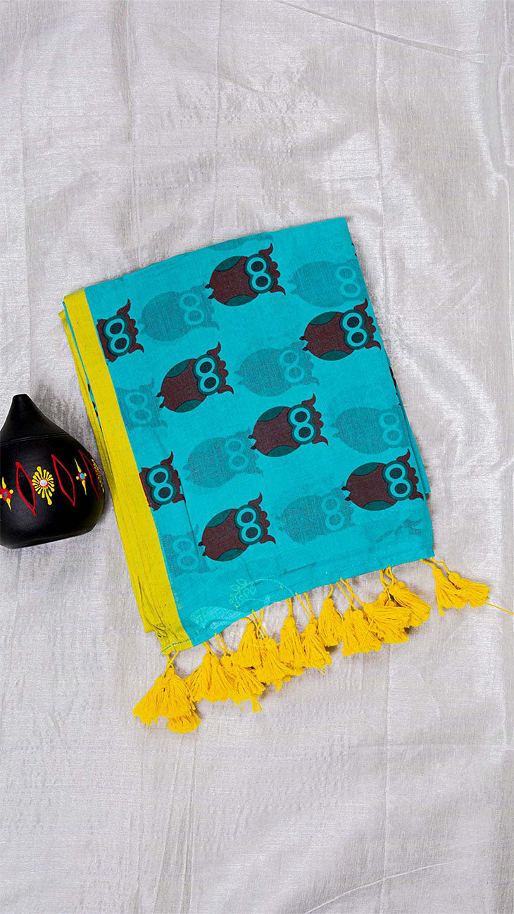 Turquoise towel with owl pattern and yellow tassels on a white fabric background