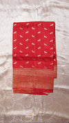 Red fabric with white patterns on a textured beige background