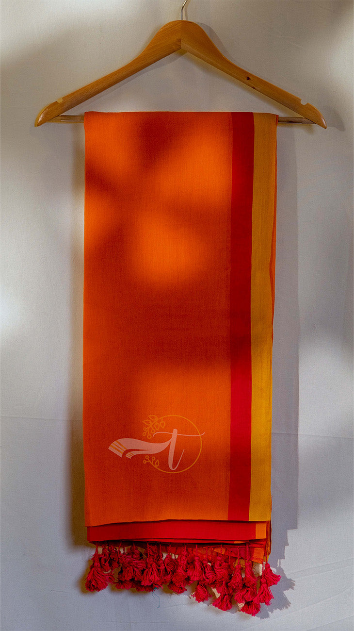 Orange scarf with red fringe on a wooden hanger against a white wall