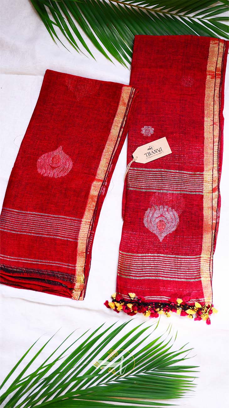 Red saree with gold border and white floral design on a white background with green leaves.