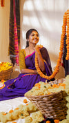 Woman in a purple saree with floral decorations in a decorated room