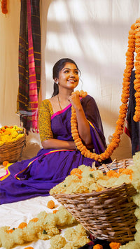 Woman in a purple saree with floral decorations in a decorated room
