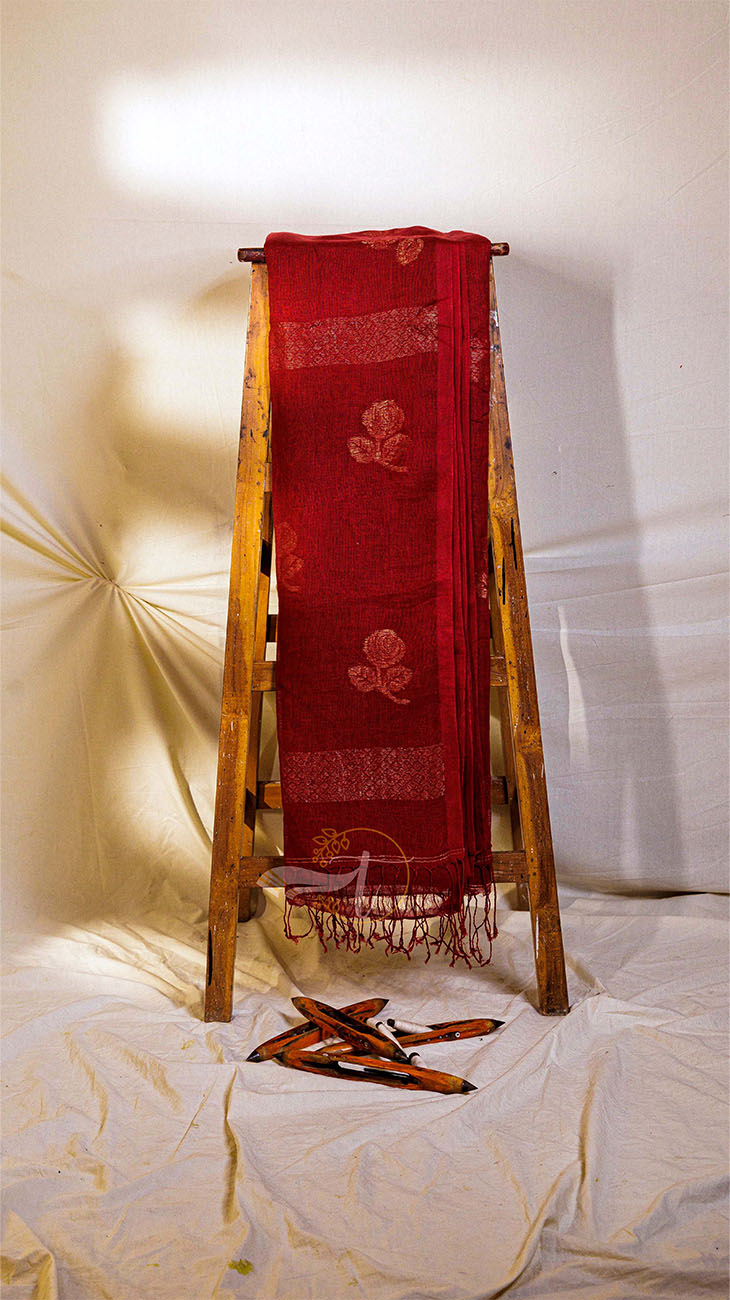 Red scarf with floral patterns on a wooden stand against a white background
