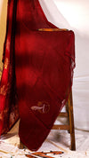 Red fabric with gold patterns draped over a wooden chair against a white background