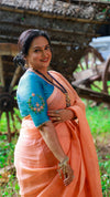 Woman in a peach saree with a blue blouse in an outdoor setting