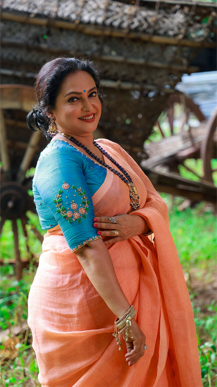 Woman in a peach saree with a blue blouse in an outdoor setting