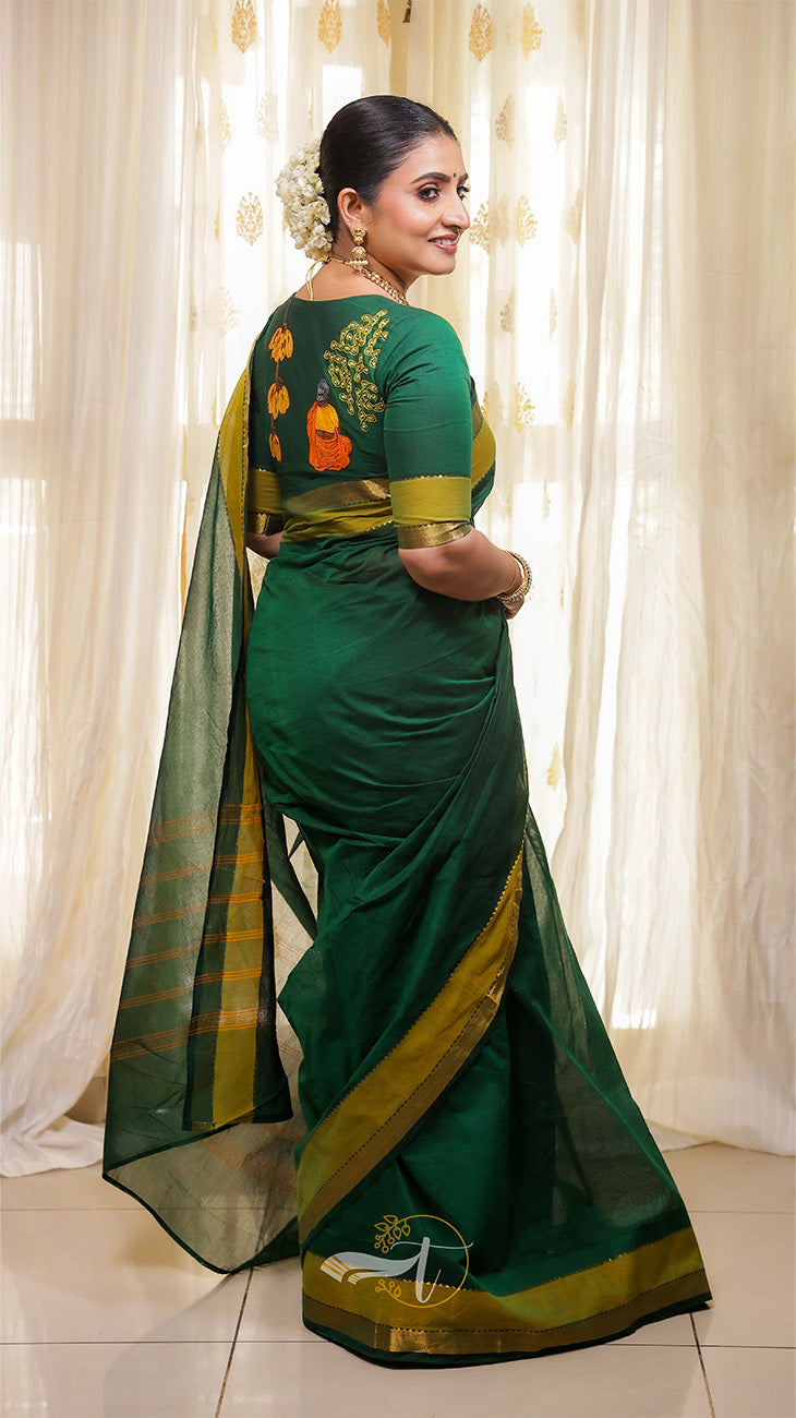 Woman wearing a green saree with gold border indoors