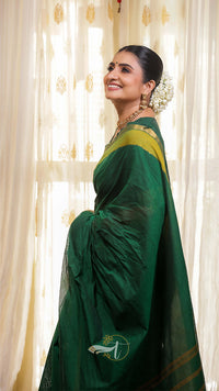 Woman wearing a green saree with a floral backdrop