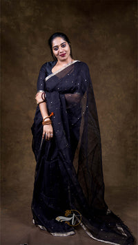 Woman wearing a black saree with a plain background