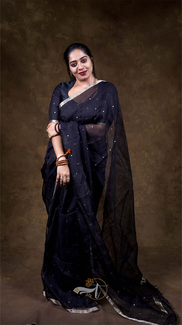 Woman wearing a black saree with a plain background