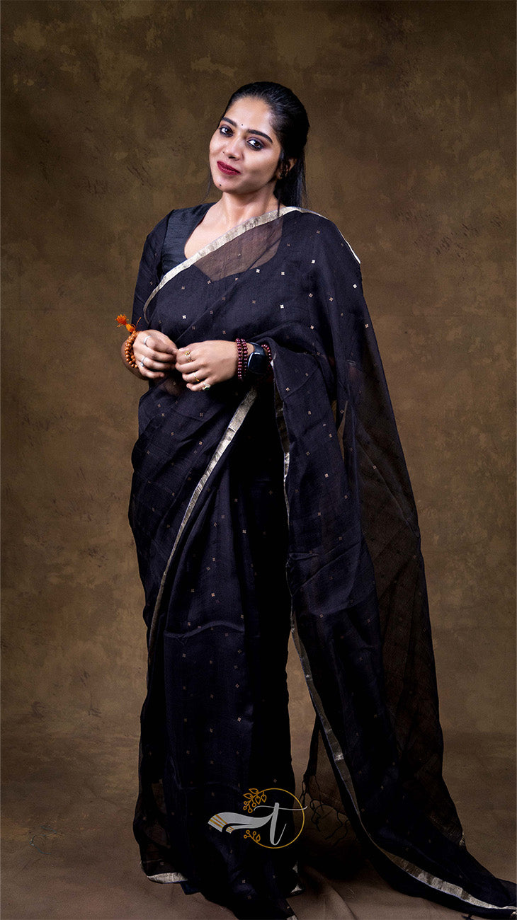 Woman wearing a black saree with a plain background