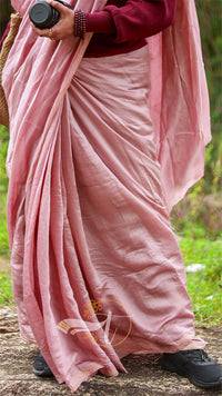 Person wearing a pink saree with a blurred natural background